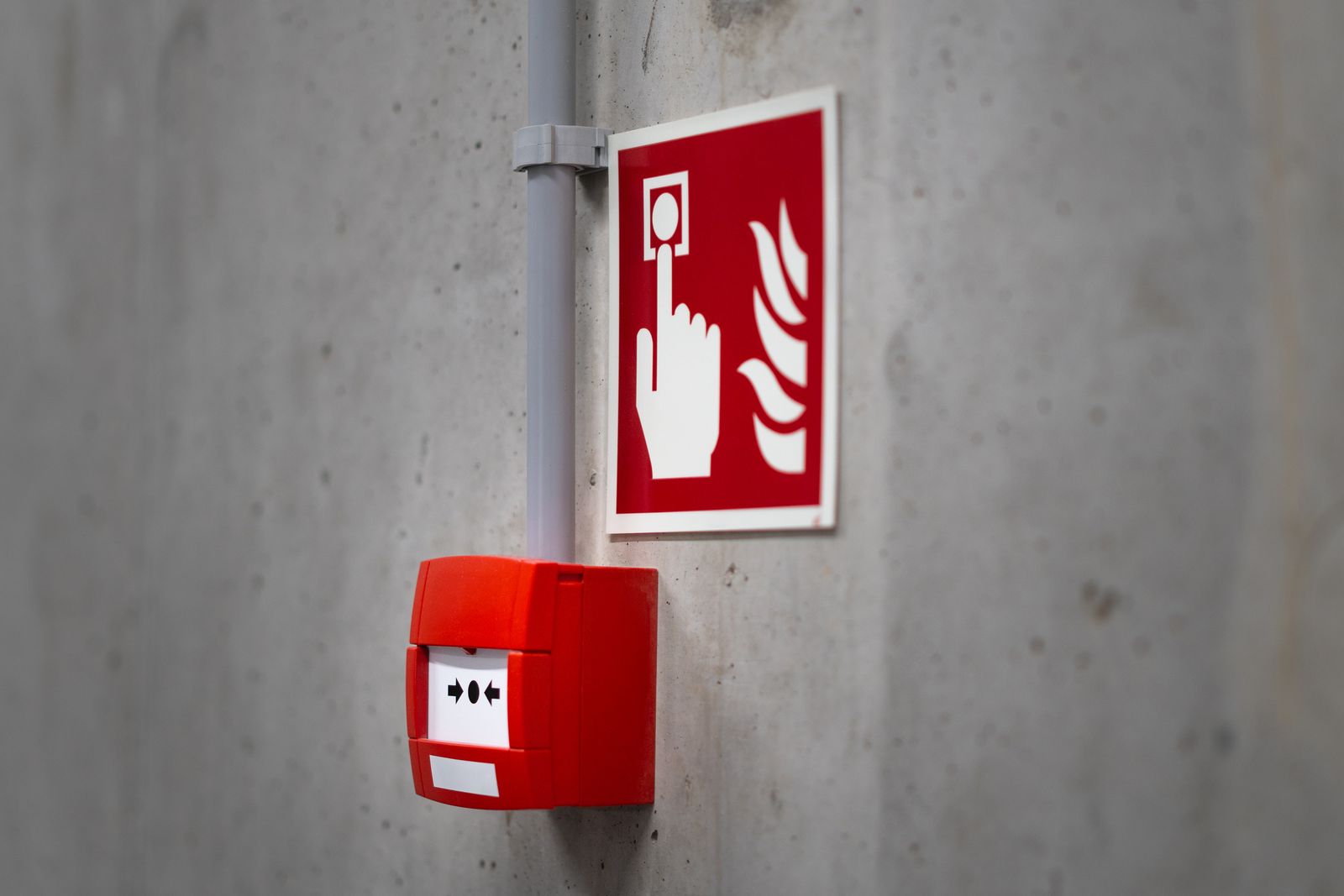 Fire alarm break-glass call point and fire alarm sign on a wall